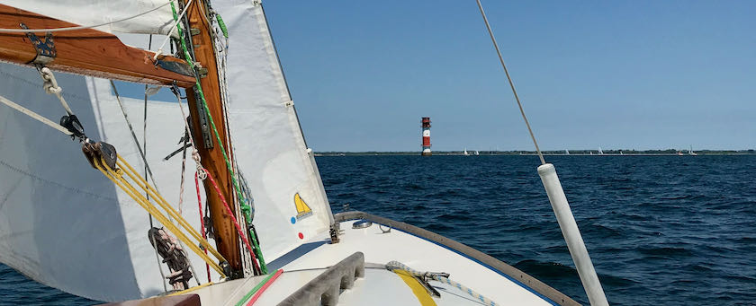 View from a sailing ship across the water spotting a lighthouse