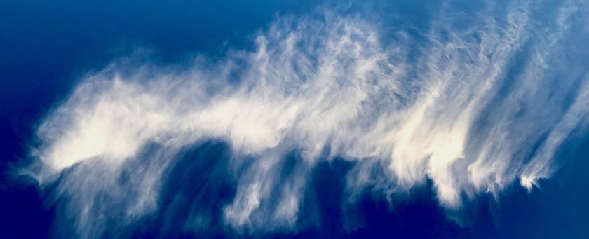 A single white cloud in a blue sky